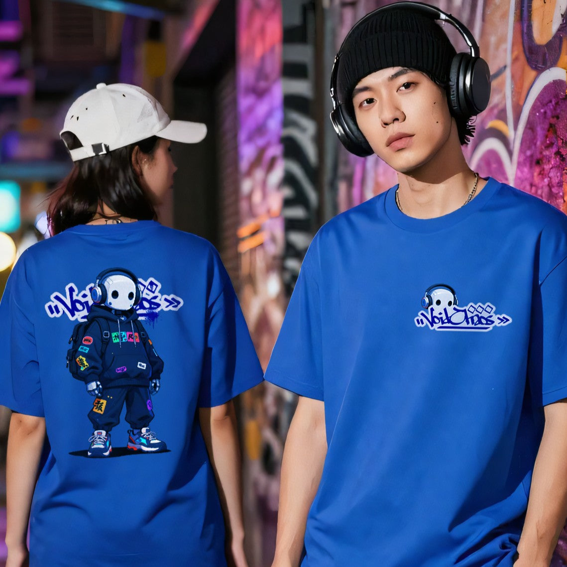 Two people wearing blue t-shirts with a cartoon character design in an urban setting.